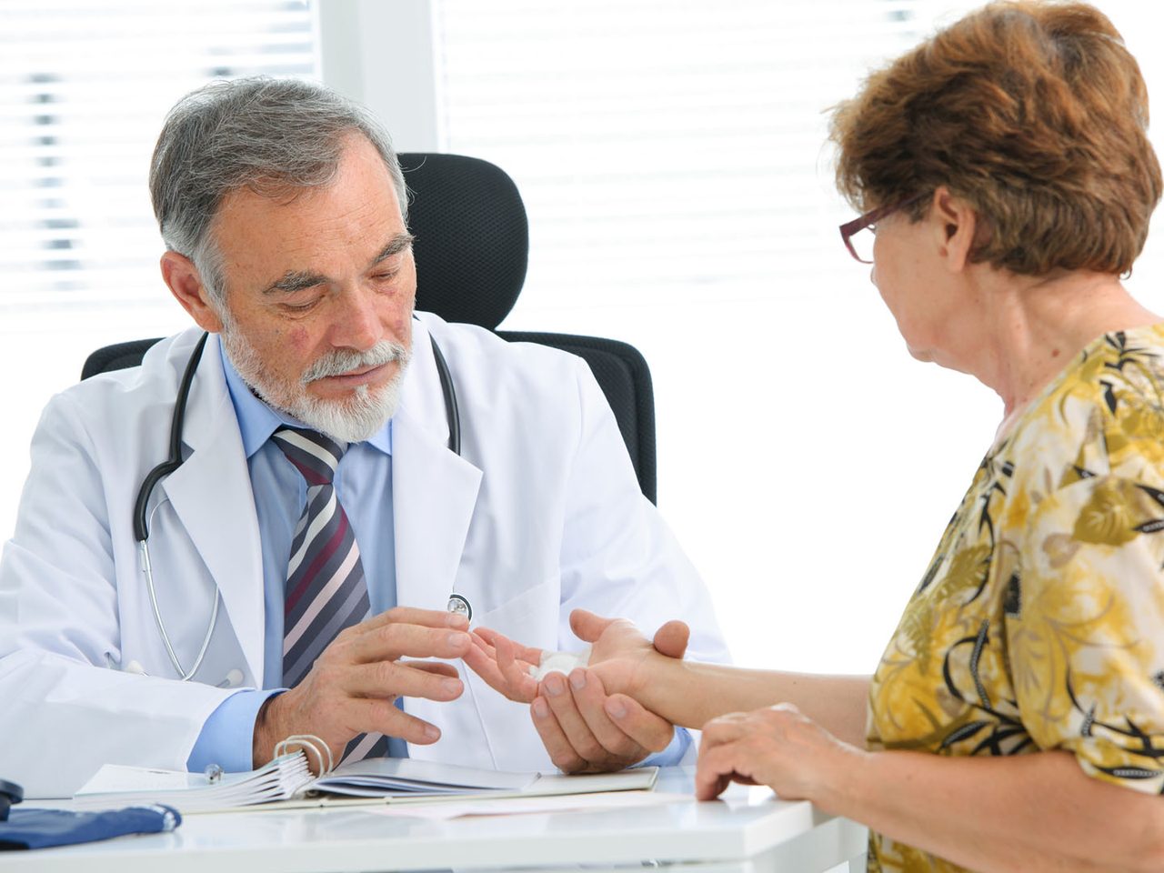 An older adult's hands resting gently over a younger person's hands